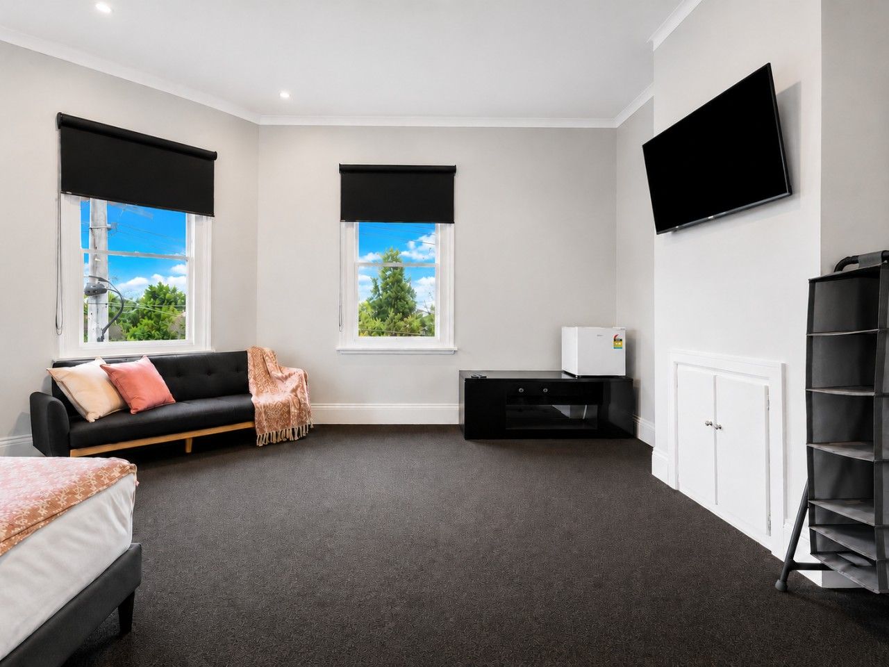 Una habitación de hotel moderna con cama, sofá, televisor, escritorio y armario.