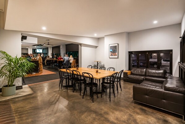 A spacious living area with a dining table, leather sofa, and a potted plant.
