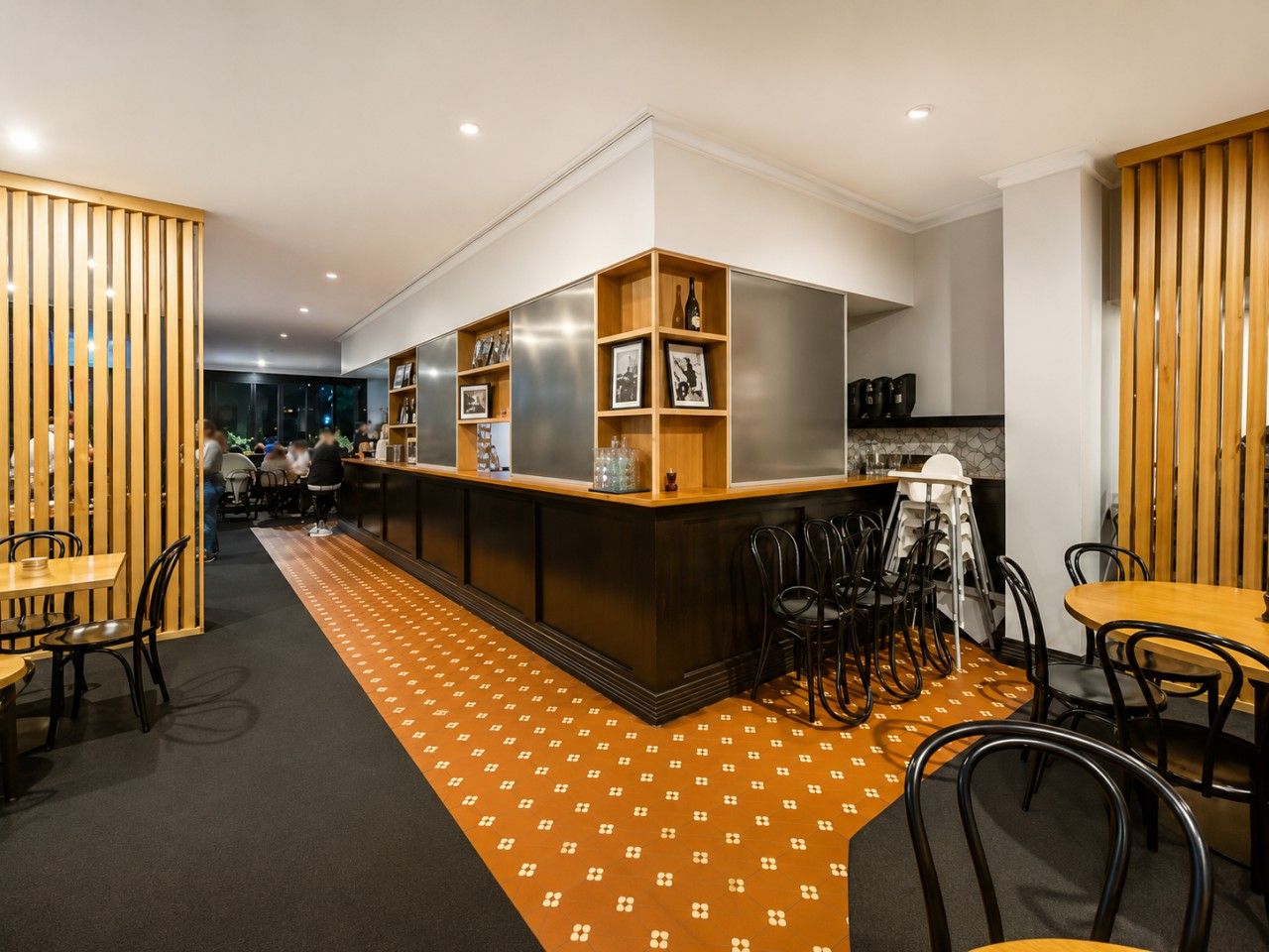 Un área de bar moderna con una barra central, arreglos de asientos y un suelo con diseño.