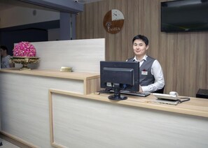A reception desk with a computer monitor, a telephone, and a nameplate. - Optima Almaty (Almaty)