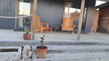A wooden deck with outdoor seating, potted plants, and a stone wall.