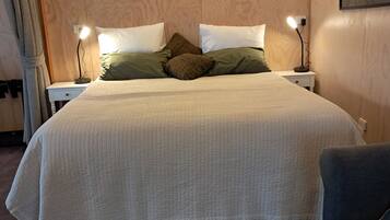 A neatly made bed with a quilted white duvet, two bedside lamps, and a nightstand with a lamp.