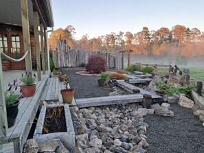 A wooden deck with potted plants and a stone pathway leading to a rustic wooden fence.