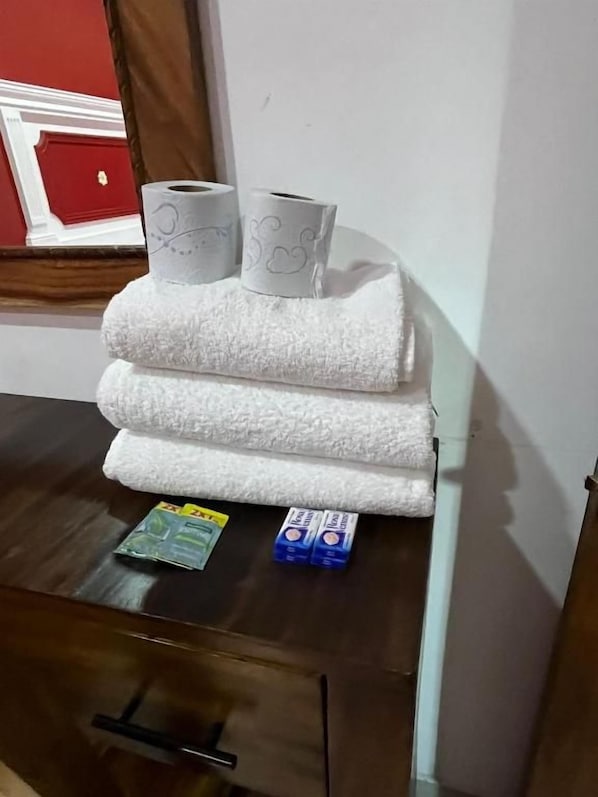 A stack of white towels on a wooden surface, a tissue box, and a small packet of tissues. - HOTEL DOÑA ANA CENTRO (Tequila)