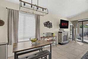 Una sala de estar con televisión, chimenea, mesa de comedor y una ventana con cortinas.