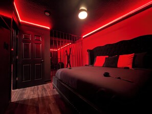 A room with a bed, a door, and a red-lit wall. - Adult Only - SPICY King Bed. Clean. Couples retreat. (Thackerville)