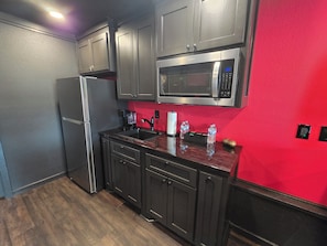 A compact kitchen with a refrigerator, microwave, and sink.
