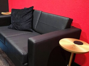 A black leather sofa with a striped pillow against a red wall. - NEW! Red Room. Spicy Couples Escape.  Clean!  King Bed. Near WinStar.  Private. (Thackerville)