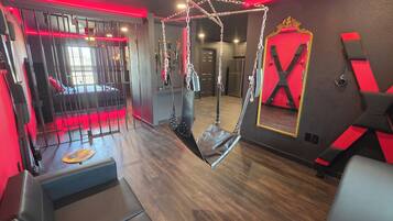 A room with a hanging chair, a mirror, and a red-lit wall.