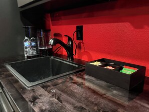 A kitchen with a black sink, a red wall, and a box of TWINING® snacks. - Adult Only - SPICY King Bed. Clean. Couples retreat. (Thackerville)