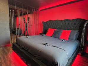 A bed with a black headboard, grey bedding, and red pillows in a room with red walls and a red-lit floor. - NEW! Red Room. Spicy Couples Escape.  Clean!  King Bed. Near WinStar.  Private. (Thackerville)