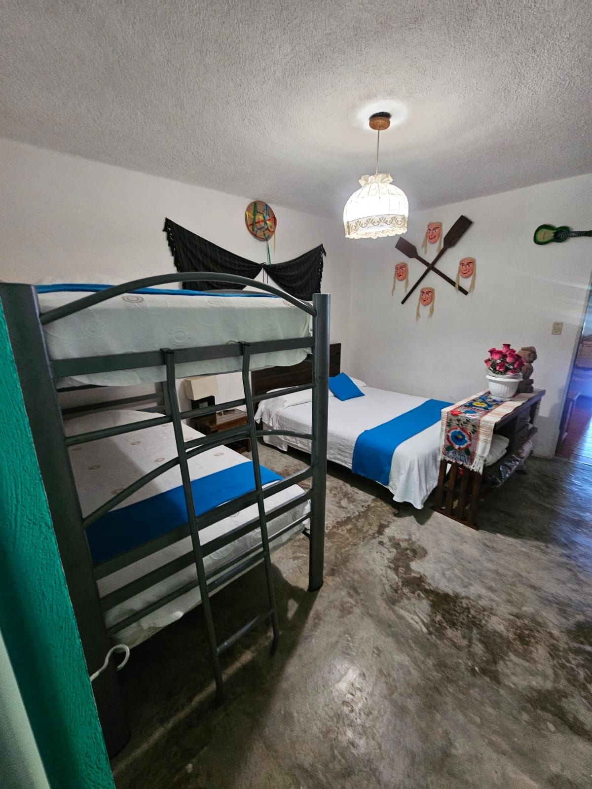 A bunk bed room with a ceiling fan, a wall-mounted decoration, and a small table with a flower arrangement.