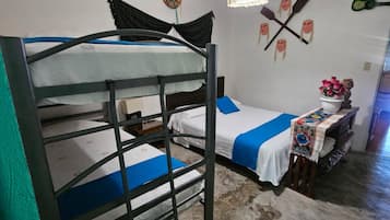 A bunk bed room with a ceiling fan, a wall-mounted decoration, and a small table with a flower arrangement.