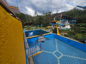 Ein Wasserpark mit mehreren Rutschen und Schwimmbecken, umgeben von viel Grün.
