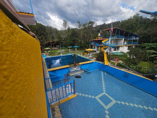 Parque acuático con múltiples toboganes y piscinas, rodeado de vegetación.