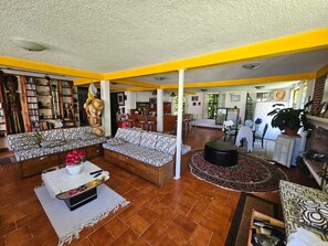 Amplia sala de estar con un conjunto de sofás, una mesa de centro con flores y un comedor con sillas y una mesa.