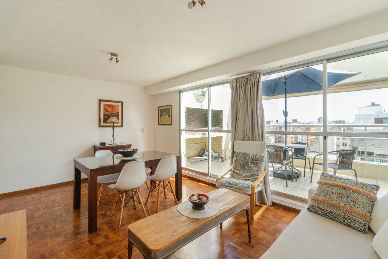Ein modernes Wohnzimmer mit Essbereich, großen Fenstern und Blick auf die Stadt.