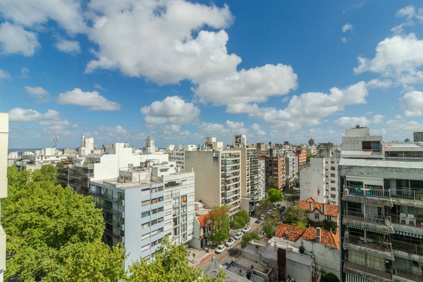 Une vue urbaine présentant divers bâtiments, notamment des immeubles résidentiels et des édifices commerciaux, sous un ciel partiellement nuageux.