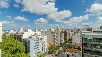 Une vue urbaine présentant divers bâtiments, notamment des immeubles résidentiels et des édifices commerciaux, sous un ciel partiellement nuageux.