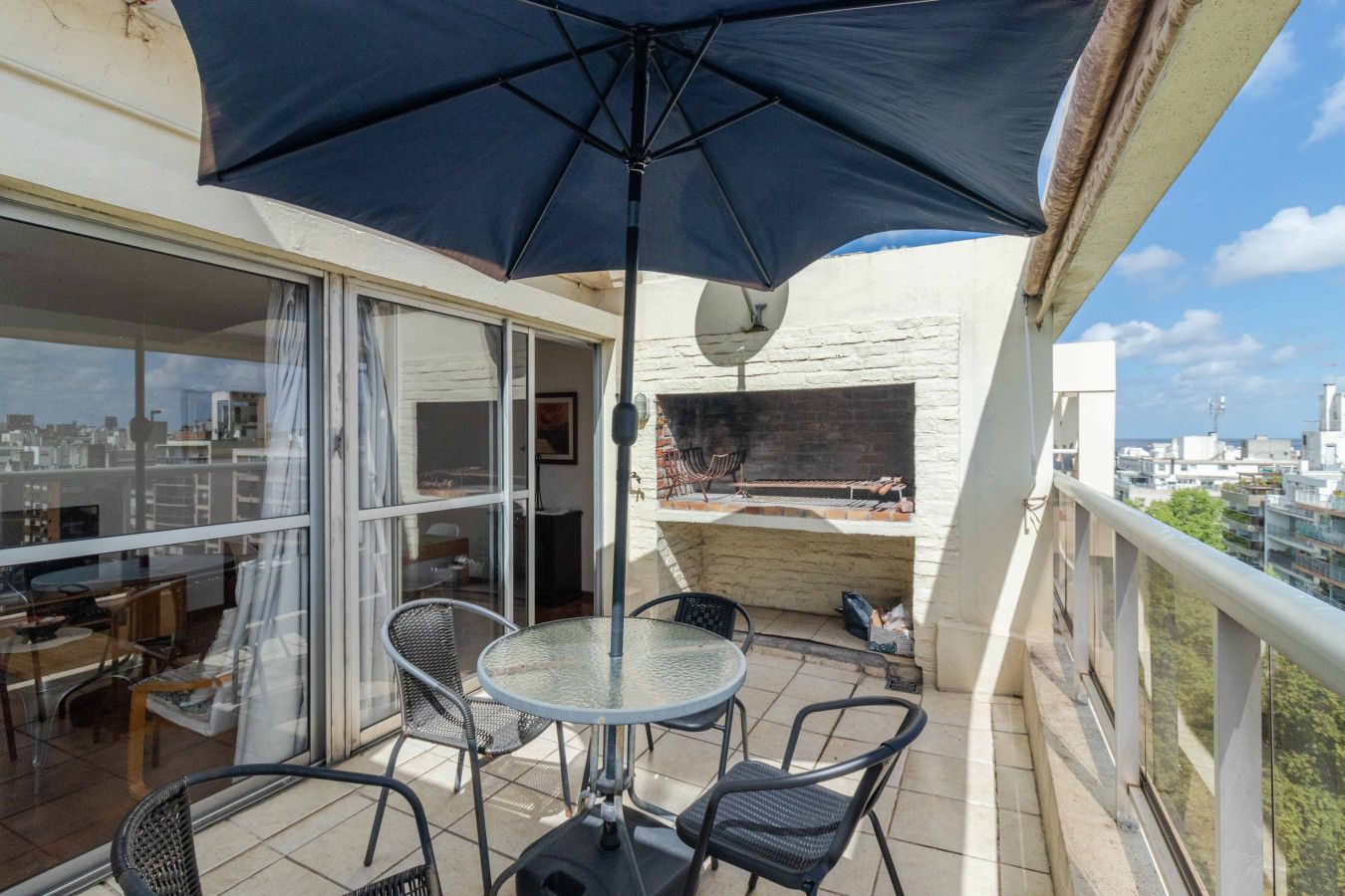 Ein Balkon mit Tisch, Stühlen, einem Grill und Blick auf die Stadt.