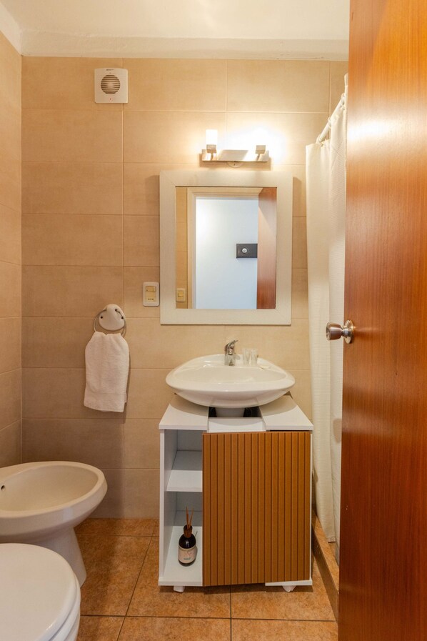 Une salle de bain équipée de toilettes, d’un bidet, d’un lavabo et d’un miroir.