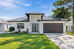 A modern two-story house with a garage, a well-maintained lawn, and a clear sky. - 4BR All-Suite Home, 5.5 Baths, Heated Pool & Spa (Bonita Springs)