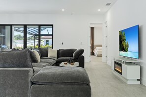 Una sala de estar moderna con un sofá seccional, un televisor de pantalla plana y una chimenea.