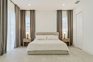 Un dormitorio moderno con una cama grande, dos mesitas de noche con lámparas y un armario.