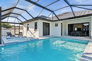 A modern house with a swimming pool, covered patio, and a dining area. - 4BR All-Suite Home, 5.5 Baths, Heated Pool & Spa (Bonita Springs)