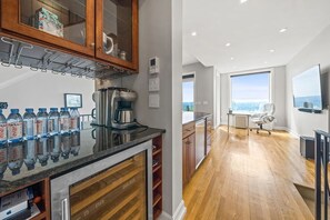 Eine moderne Küche mit Kaffeemaschine, Wasserflaschen und Blick zum Wohnbereich.