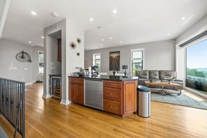 Eine moderne Küche mit Holzausstattung, einem Edelstahlkühlschrank und einer zentralen Kochinsel mit Spüle.