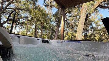 A hot tub under a wooden canopy surrounded by trees.