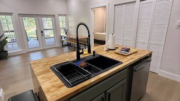 A modern kitchen with a wooden countertop, a sink, and a dishwasher.