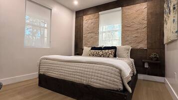 A bedroom with a bed, a ceiling fan, a window, and a wall-mounted shelf.