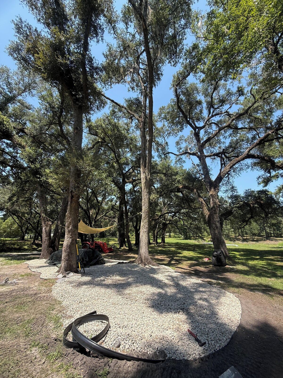A park with trees, a gravel area, and a red vehicle.