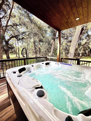 Un bain à remous sur une terrasse en bois, avec vue sur les arbres.