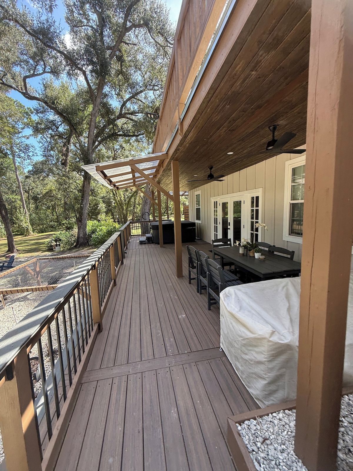 A wooden deck with outdoor seating, a covered area, and a view of trees.