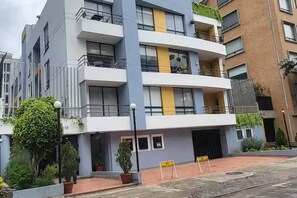 A multi-story residential building with balconies, potted plants, and a paved entrance area. - New Listing (Bogotá)