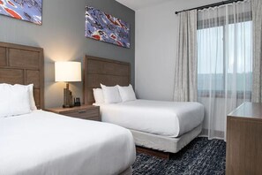 A hotel room with two beds, a nightstand, a lamp, and a window with sheer curtains. - Glacier Canyon  Wilderness Waterpark Wisconsin Dells, 2 BR 1,500 sq ft Condo (Baraboo)