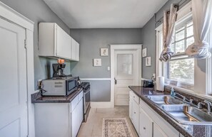 A compact kitchen with white cabinets, a microwave, a stove, and a sink. - 10 Min to U of Memphis-Rozelle Retreat Both Units (Memphis)