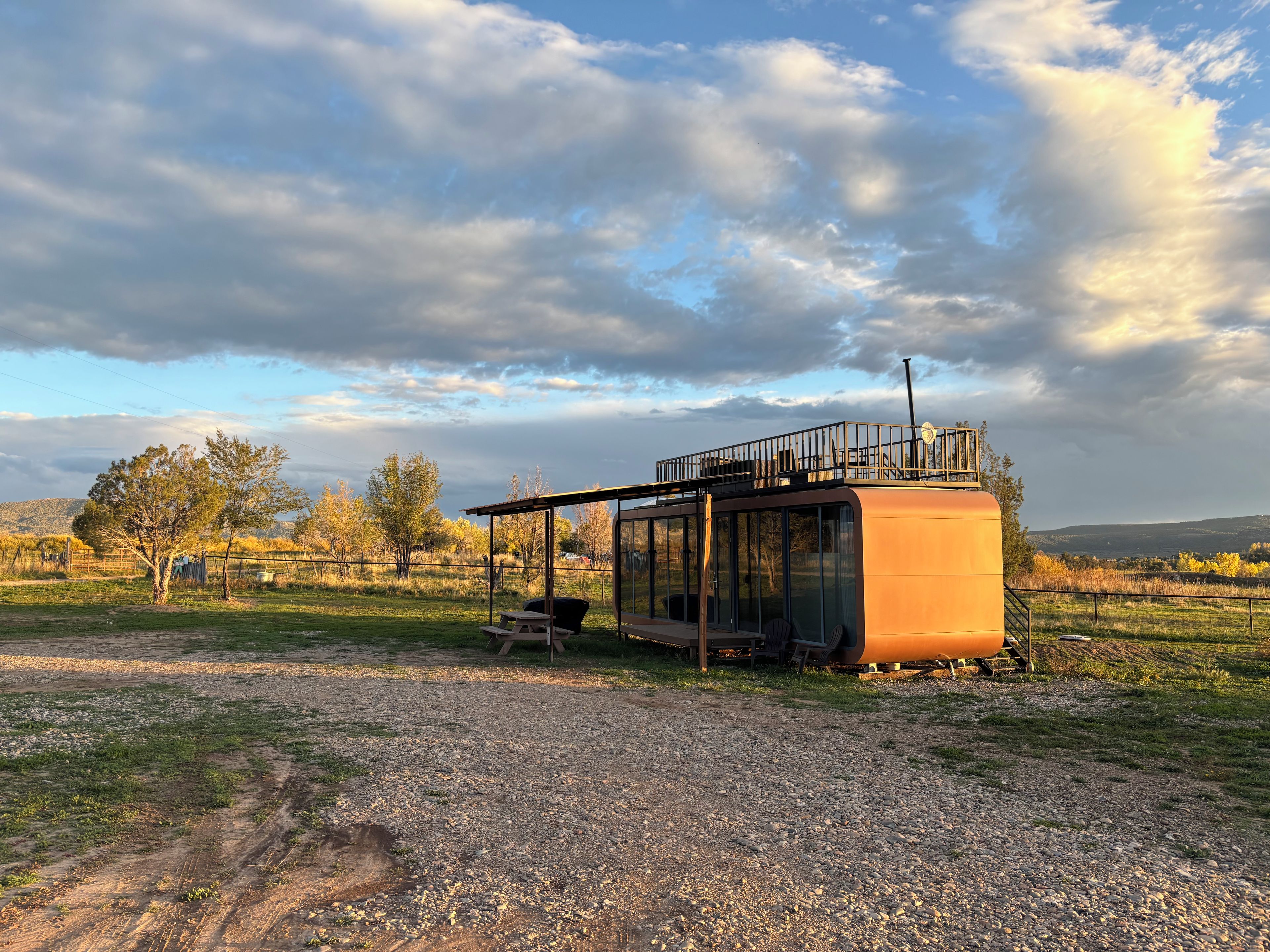Una cabaña rústica con un porche cubierto, una mesa de picnic y vistas del paisaje circundante.