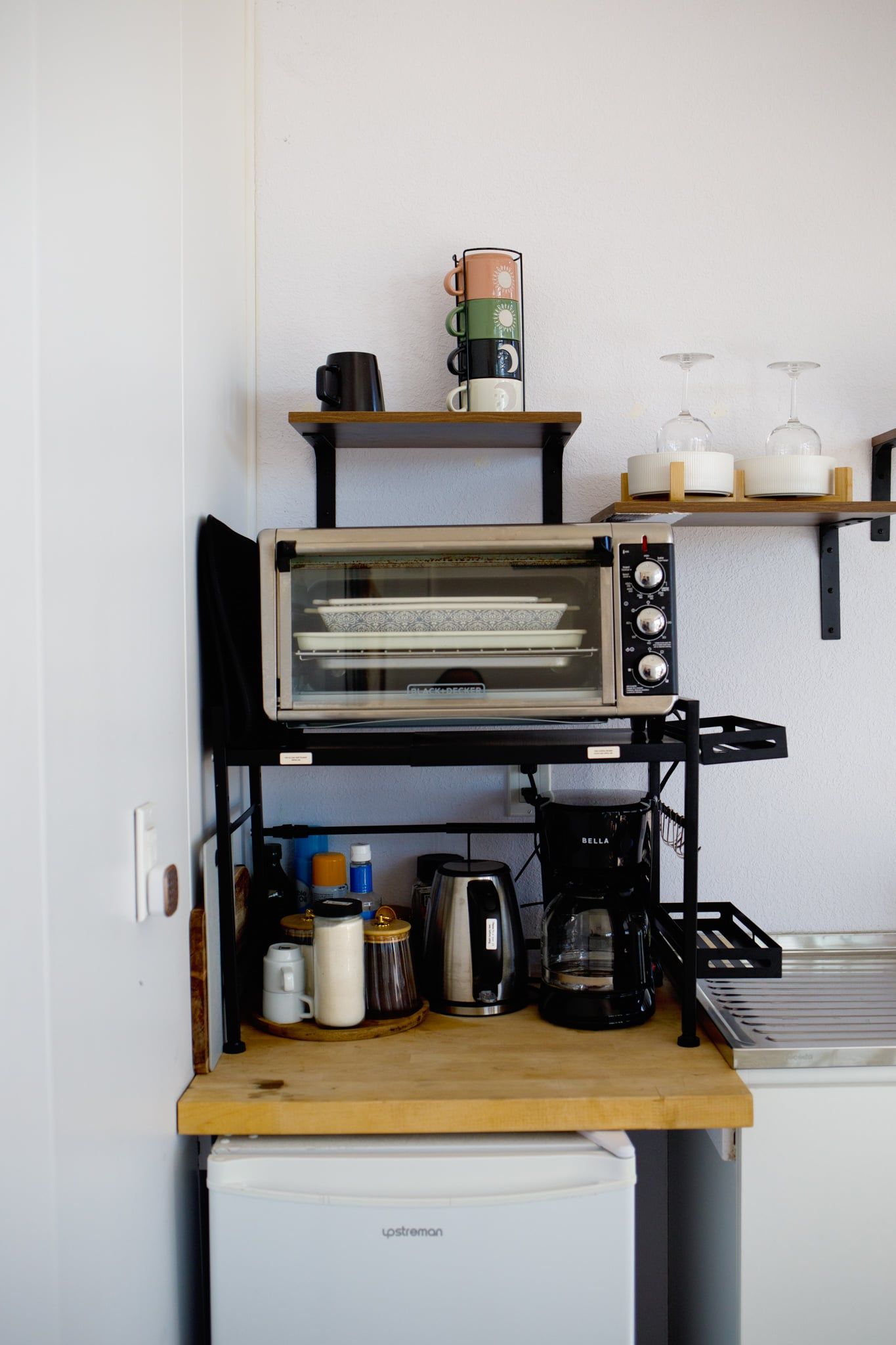 A kitchenette with a toaster oven, coffee maker, and various kitchen items on a wooden countertop.