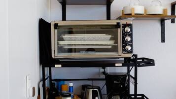 A kitchenette with a toaster oven, coffee maker, and various kitchen items on a wooden countertop.