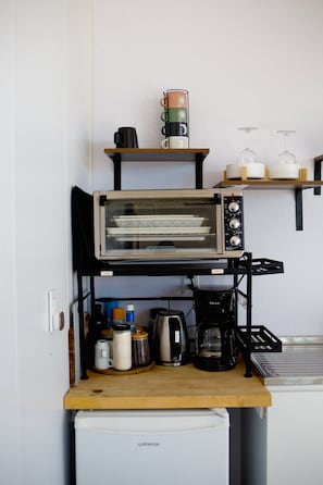Een kitchenette met een broodroosteroven, koffiezetapparaat en diverse keukengerei op een houten aanrecht.