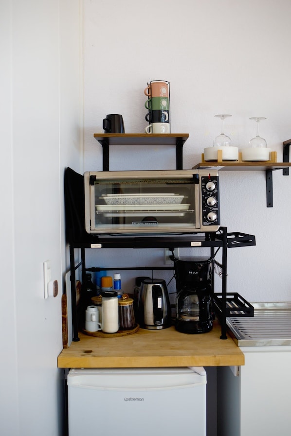 A kitchenette with a toaster oven, coffee maker, and various kitchen items on a wooden countertop.