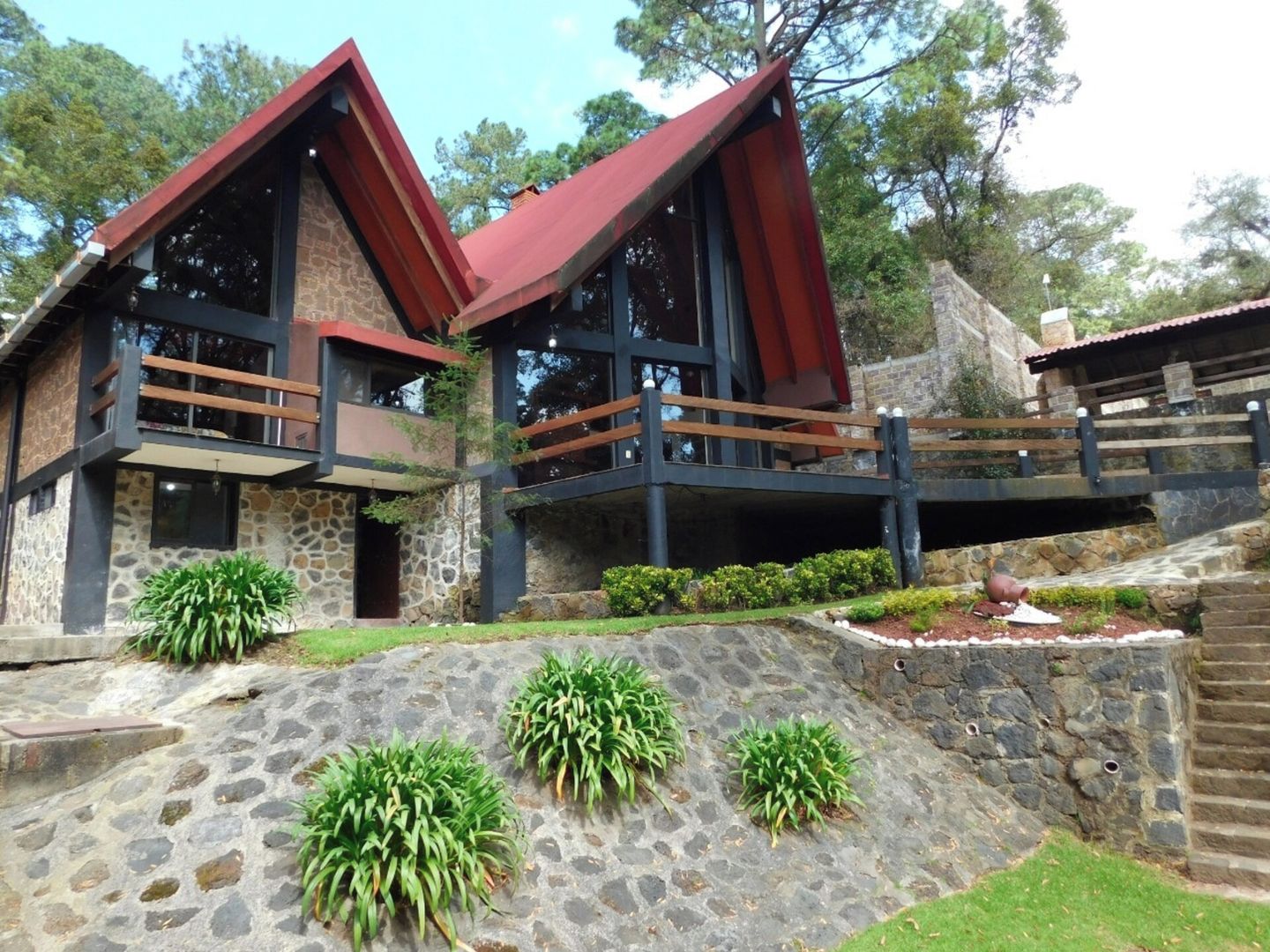 A two-story stone building with a red roof and a balcony.