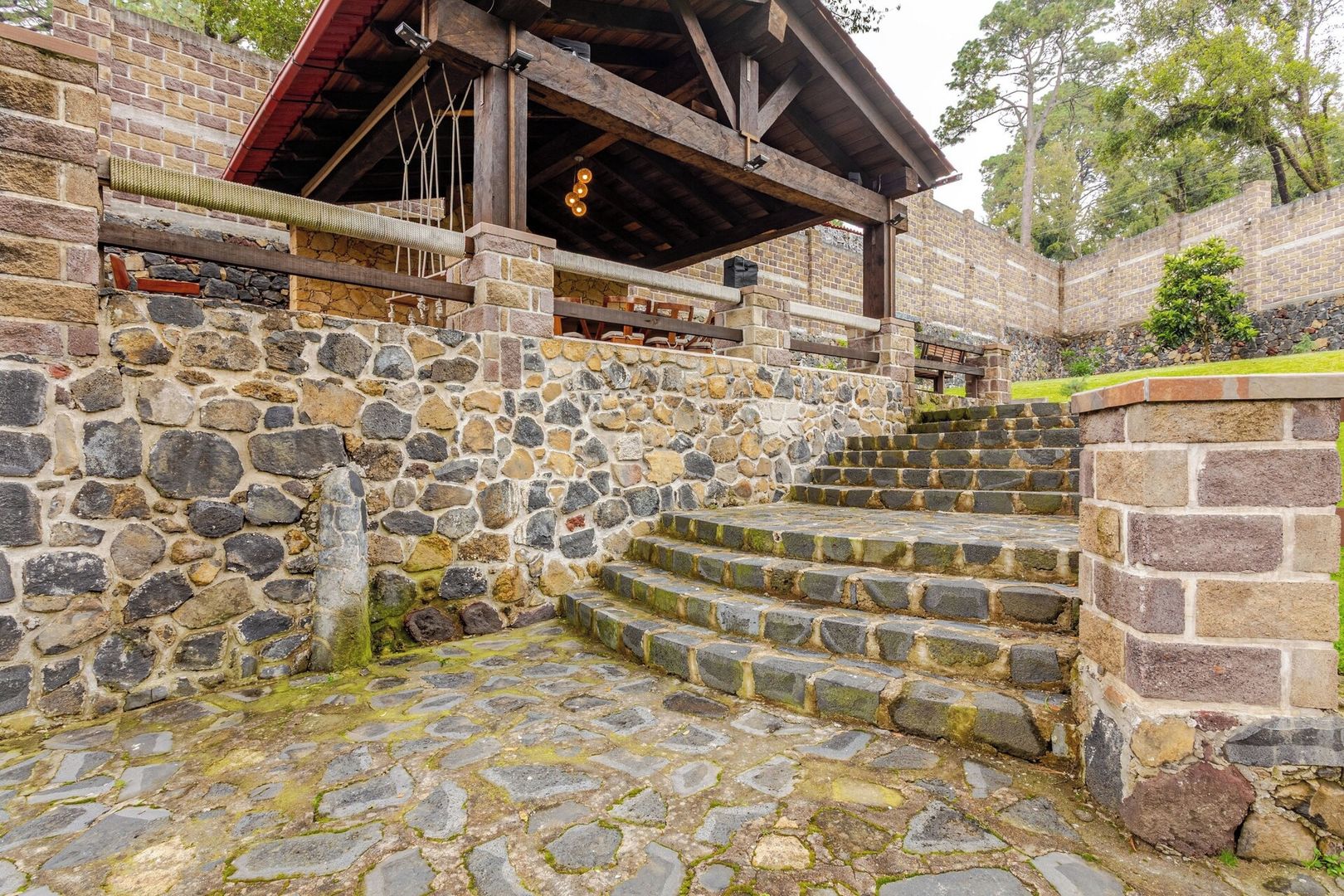 A stone staircase leading to a wooden structure with a red roof.