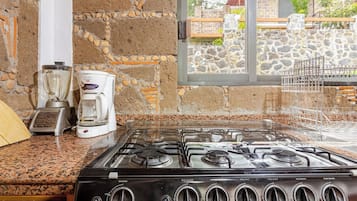 Une cuisine équipée d’une cuisinière à gaz, d’une machine à café et d’un mur en pierre.