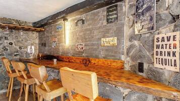 Uma área de bar com cadeiras de madeira e uma parede de pedra.
