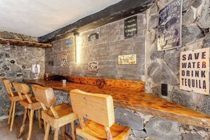 A bar area with wooden chairs and a stone wall. - Forest cabin for groups · hot tub and fire pits (Tres Marias)
